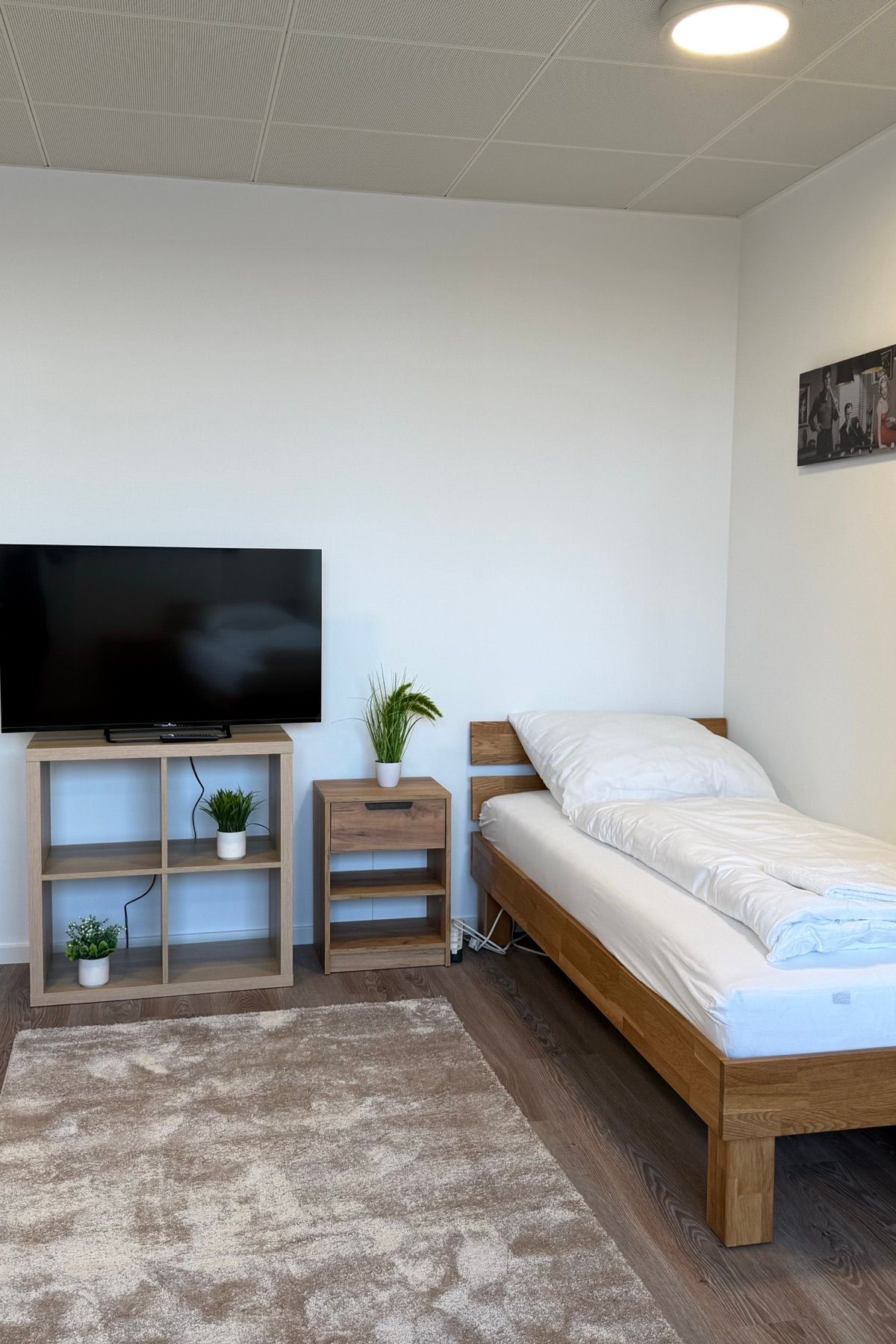Część mieszkalna z pojedynczym łóżkiem, telewizorem i szafą w umeblowanym apartamencie MA-Flats