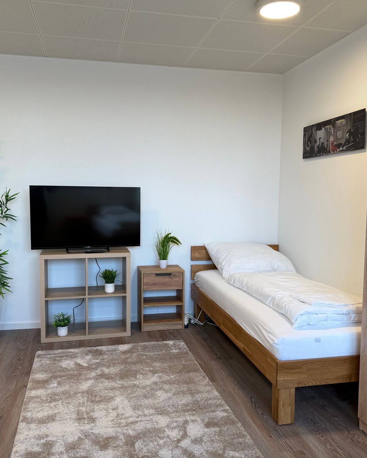 Wohnbereich mit Einzelbett, Fernseher und Kleiderschrank in einem möblierten MA-Flats Apartment