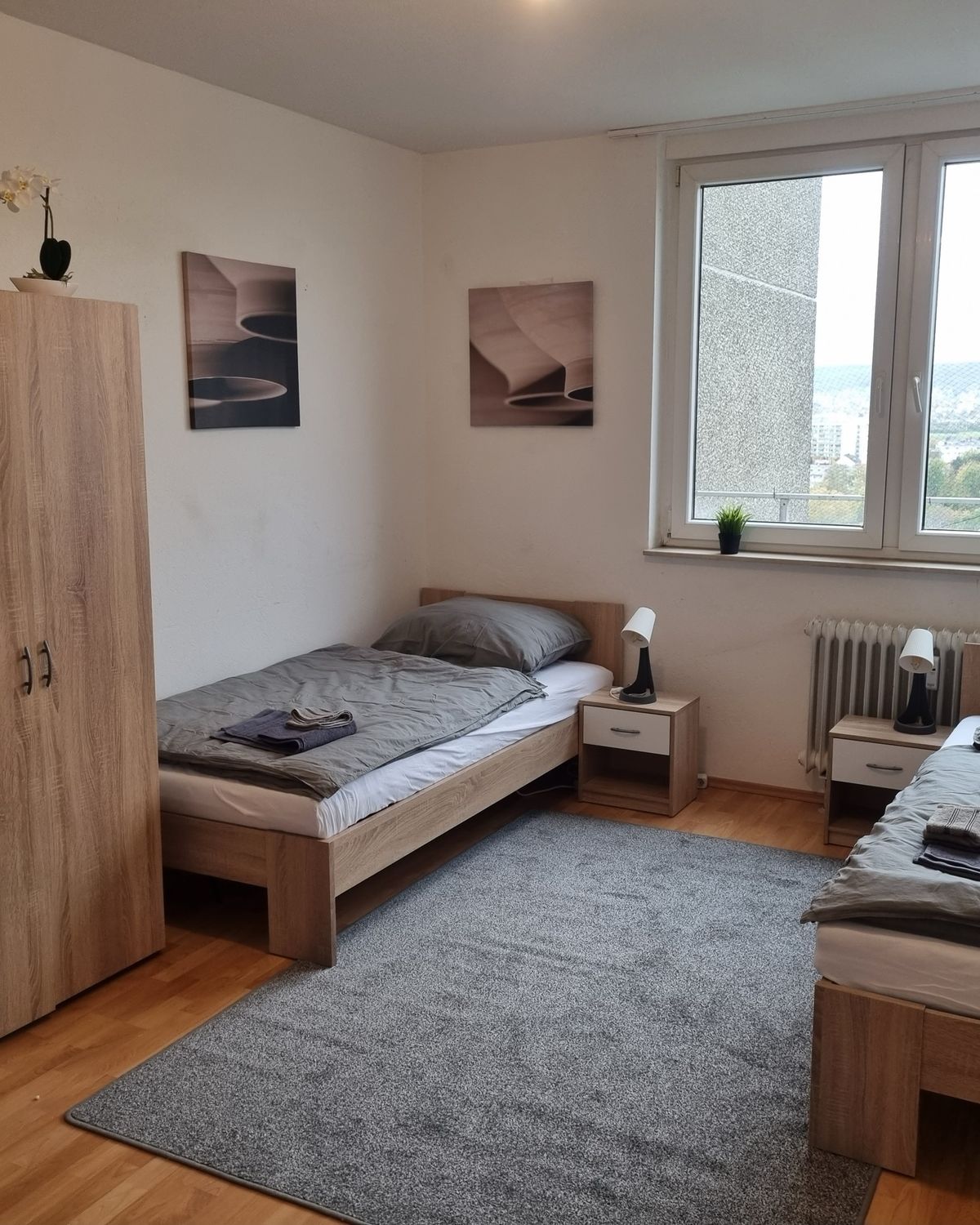 Helles Zweibettzimmer mit Kleiderschrank und Fensterblick in einem MA-Flats Apartment