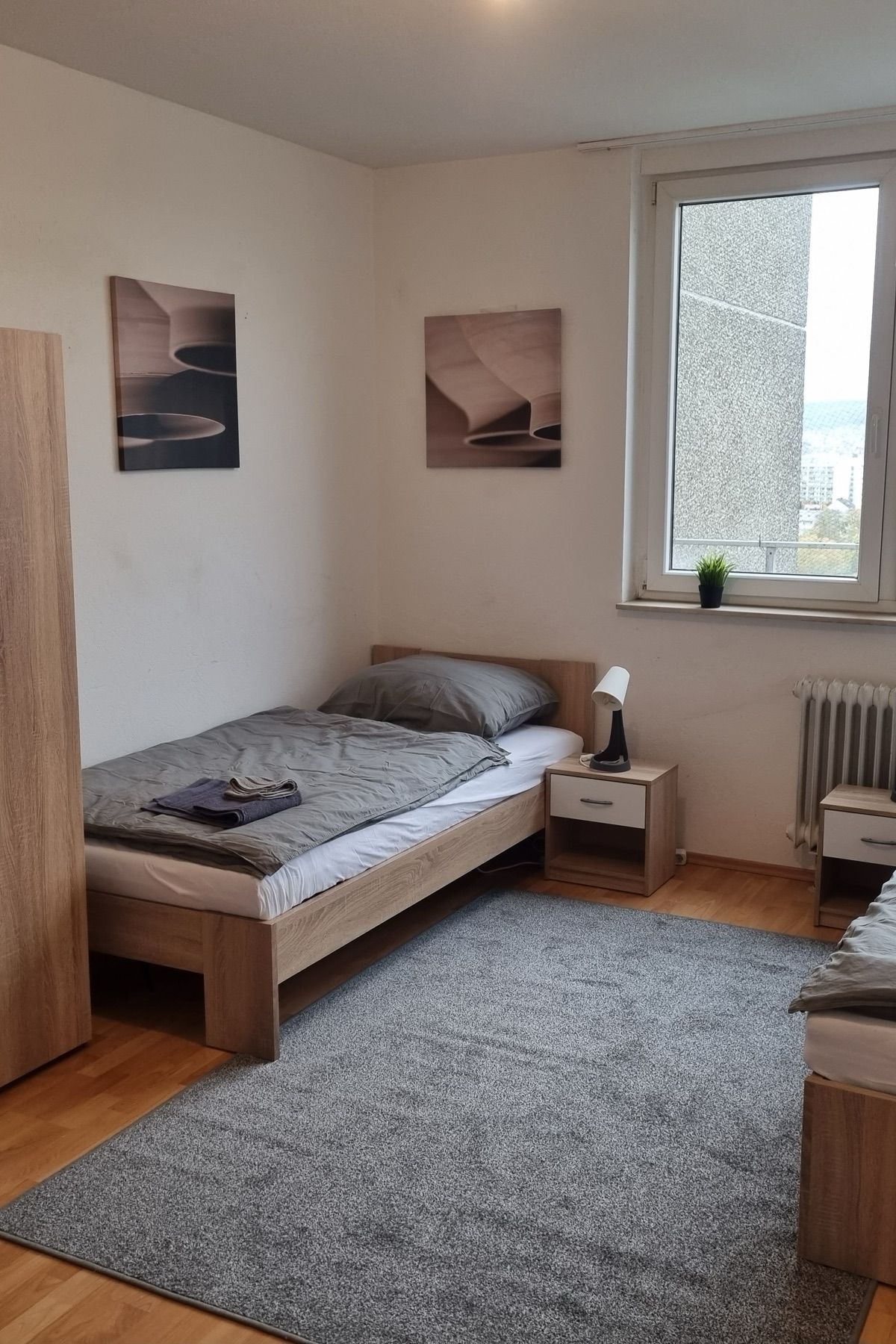 Helles Zweibettzimmer mit Kleiderschrank und Fensterblick in einem MA-Flats Apartment