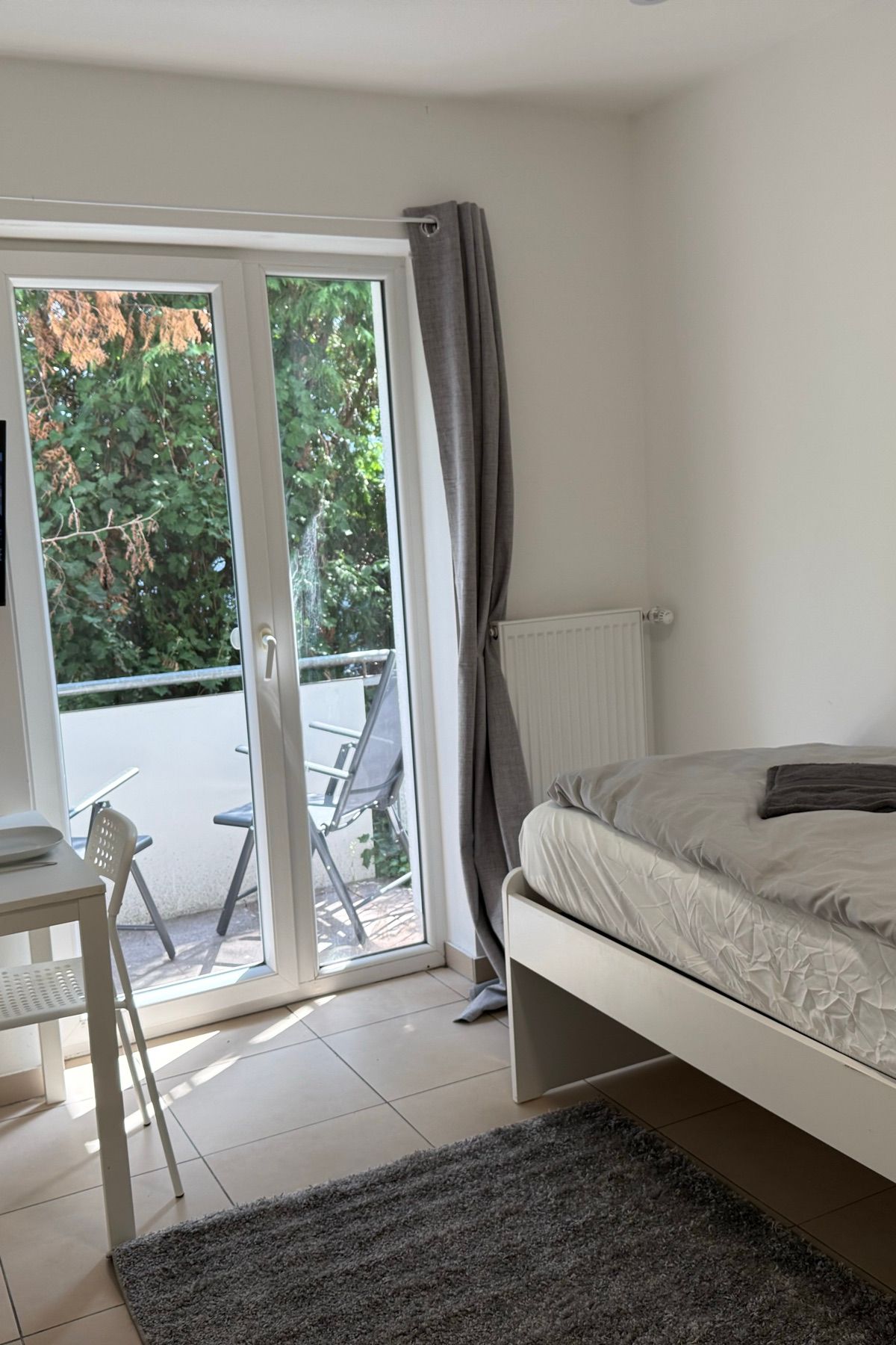 Einzelzimmer mit Balkontür, Schreibtisch und Fernseher in einem MA-Flats Apartment