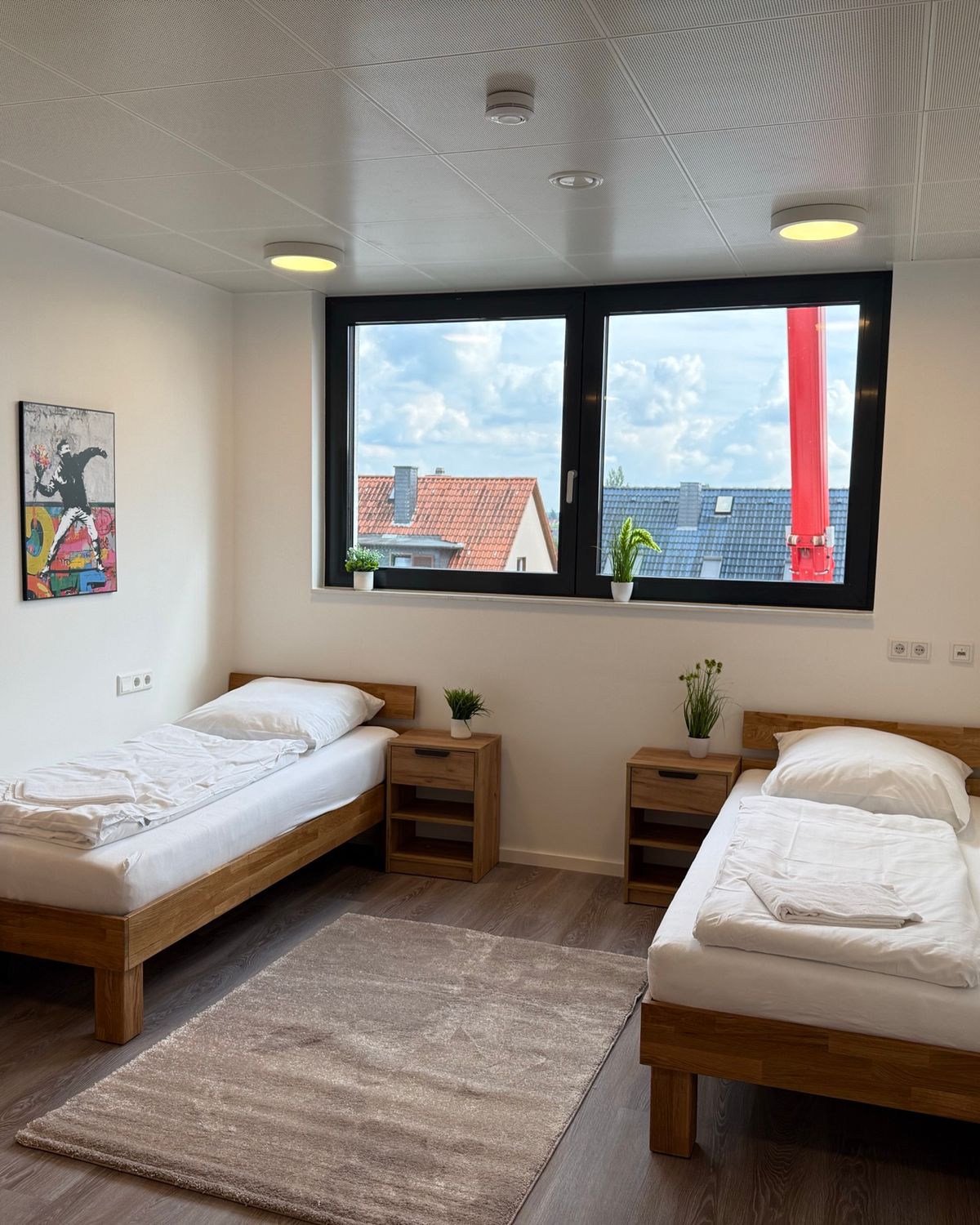 Helles Zweibettzimmer mit gemachten Betten und Fensterblick in einem MA-Flats Apartment