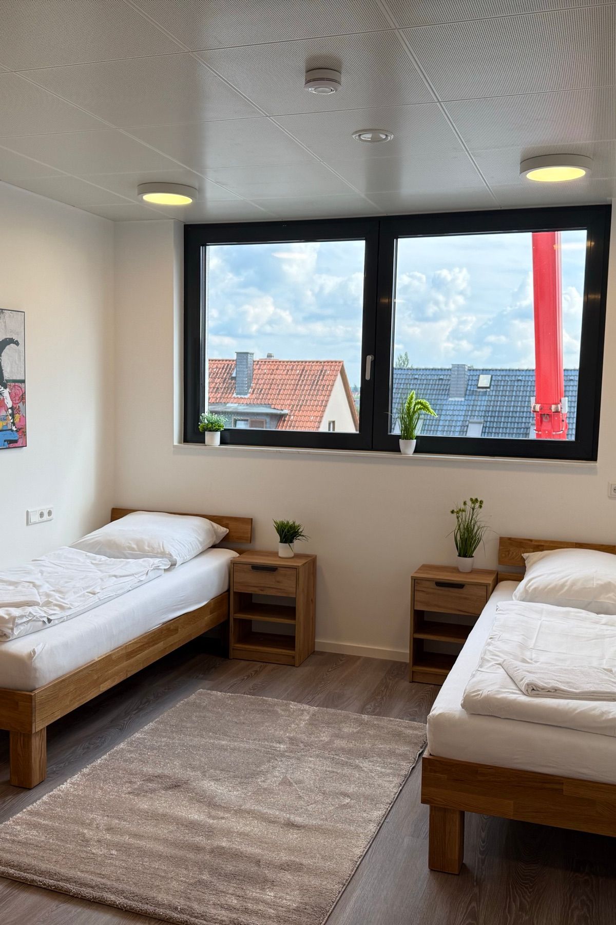 Bright twin room with made-up beds and a window view in an MA-Flats apartment