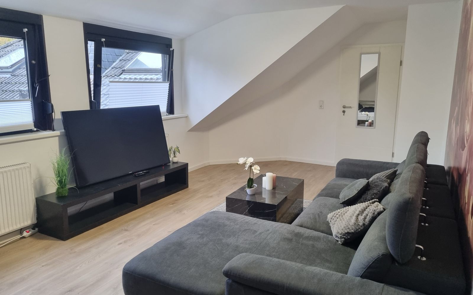 Wohnzimmer mit großem Ecksofa und Fernseher in einem möblierten MA-Flats Apartment