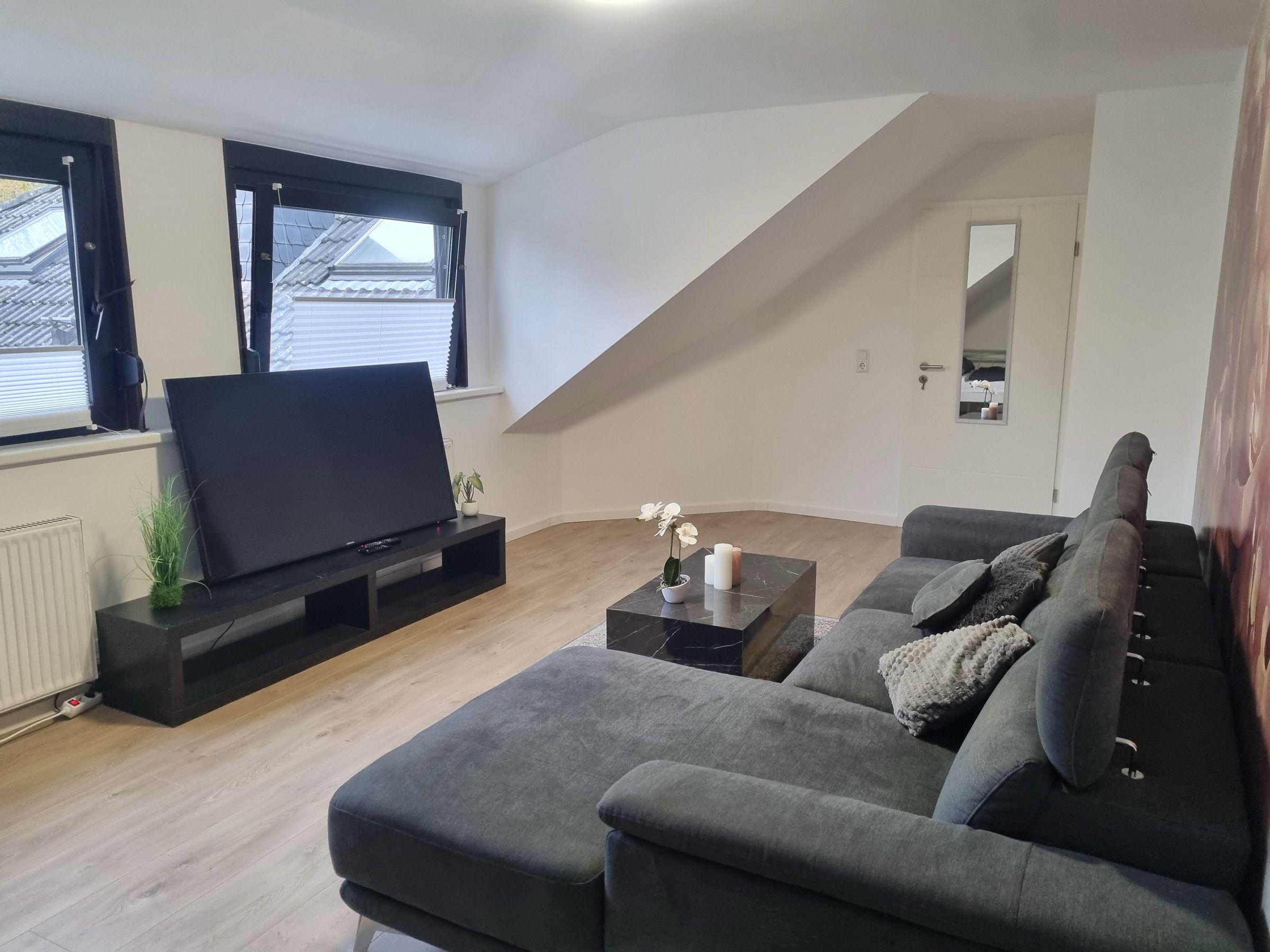 Wohnzimmer mit großem Ecksofa und Fernseher in einem möblierten MA-Flats Apartment